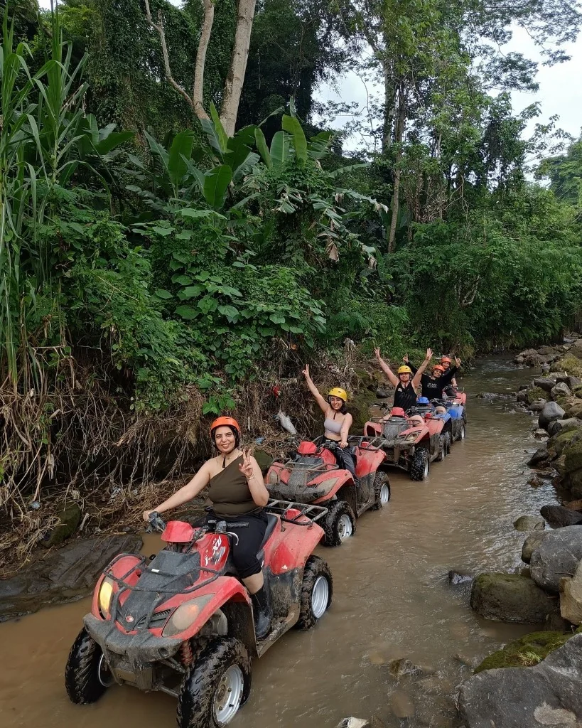 Convoy of ATV riders navigating shallow river canyon in Ubud Bali jungle